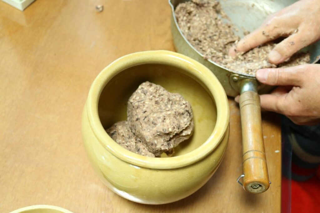 黒豆味噌作り方　味噌玉を団子状にして容器に詰めている様子